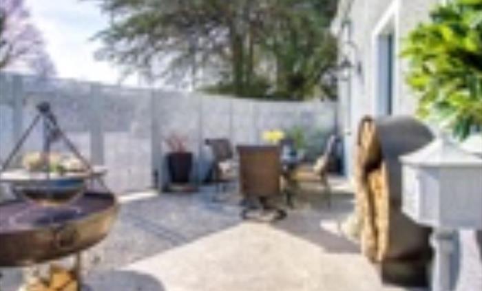 Private patio area containing Kadai, firepit, pizza oven, log store and dining table